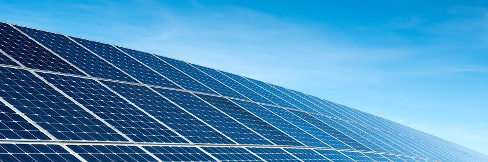 Nahaufnahme von Solaranlagen vor einem strahlend blauen Himmel.